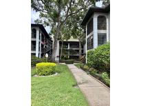 Condo building featuring well-manicured lawns, lush landscaping, and a charming walkway leading to the units at 3399 Mermoor Dr # 207, Palm Harbor, FL 34685