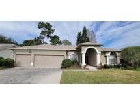 Charming single-story home featuring a three-car garage, manicured lawn, and inviting front entrance at 4467 Worthington Ct, Palm Harbor, FL 34685