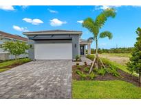 Modern home with gray exterior and paver driveway at 11216 Livewell Ct, Venice, FL 34293