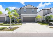 Two-story home with gray exterior, two-car garage, and landscaping at 16764 Delia St, Wimauma, FL 33598