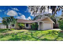 Tan one-story house with a two-car garage and lush lawn at 6969 Oldgate Cir, New Port Richey, FL 34655