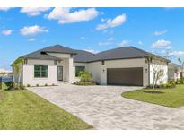 White one-story home with dark gray metal roof, paver driveway & landscaping at 1810 4Th E St, Palmetto, FL 34221