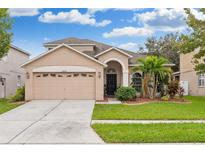 Two-story house with a two-car garage, landscaping, and palm trees at 30552 Latourette Dr, Wesley Chapel, FL 33545