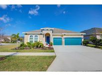 Charming single-story home featuring a blue garage door, arched windows, and a well-manicured lawn at 5502 Limelight Dr, Apollo Beach, FL 33572