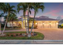 Elegant home features a tile roof, three-car garage, and lush landscaping with palm trees and paver driveway at 7925 Royal Queensland Way, Lakewood Ranch, FL 34202