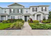 Charming townhome featuring a manicured lawn with lush landscaping, a walkway, and pleasant curb appeal at 14929 Promenade Pkwy, Odessa, FL 33556