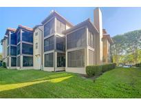 Tan building with multiple screened balconies and lush green landscaping at 2400 Feather Sound Dr # 211, Clearwater, FL 33762