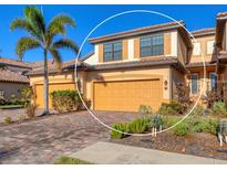 Charming two-story home with a two-car garage, beautiful landscaping, and a brick driveway with a palm tree at 20180 Ragazza Cir # 201, Venice, FL 34293