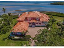 Stunning waterfront property with a clay tile roof, lush landscaping, and a spacious driveway at 3418 Braeside Pl, Clearwater, FL 33759