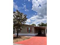 Charming single-story home with a red driveway and beautiful landscaping with a tree in the front yard at 36822 Kay Ave, Zephyrhills, FL 33542