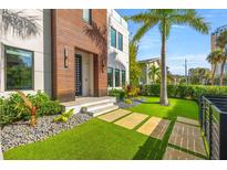Modern home featuring an artificial turf lawn with stone walkways, lush landscaping, and a wood facade at 103 5Th N Ave, St Petersburg, FL 33701
