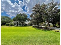 Expansive lawn and mature trees complement this single-story home with a classic architectural design at 168 Rue Des Chateaux, Tarpon Springs, FL 34688