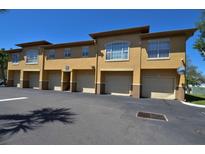 Exterior view of a well-maintained building with multiple garages and stucco facade under a clear blue sky at 4336 Bayside Village Dr # 201, Tampa, FL 33615