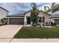 Single-story home with two-car garage and well-manicured lawn at 14906 Imperial Purple Ln, Wimauma, FL 33598