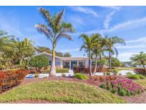 Charming single-story home with well-manicured landscaping, healthy palm trees, and inviting blue double-door entry at 165 4Th N Ave, Tierra Verde, FL 33715