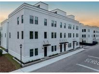 Modern three-story townhouse with white brick facade, black framed windows, and manicured landscaping at 1218 E Kay St # 3, Tampa, FL 33602