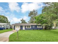 Charming Ranch style home with blue exterior, two car garage, and a well-manicured lawn at 39035 Citadel Cir, Zephyrhills, FL 33542