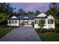 Charming single-story home with a brick driveway, manicured lawn, and classic white facade against a colorful sunset at 4586 Hickory Oak Dr, Brooksville, FL 34601