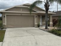 Tan house with two-car garage and landscaping at 6812 Aramon Ct, Wesley Chapel, FL 33545
