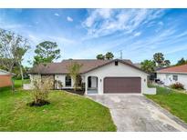 Newly renovated home with a landscaped lawn and attached garage at 4501 Harrington St, Port Charlotte, FL 33948