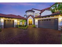 Elegant home featuring a brick driveway, three-car garage, stone accents, and a barrel tile roof at dusk at 8414 Dunham Station Dr, Tampa, FL 33647