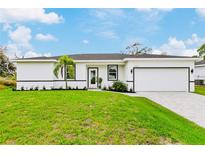 White house with gray roof, paved driveway, and grassy lawn at 5221 Chaney Ter, Port Charlotte, FL 33981