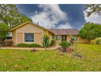 Tan brick ranch home with landscaped yard and walkway at 1220 Bluefield Rd, Odessa, FL 33556