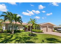 Tan house with two-car garage, palm trees, and landscaped lawn at 237 2Nd W St, Tierra Verde, FL 33715