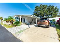 Front view of a manufactured home with a covered carport and landscaping at 37827 Mission Hills Ave, Zephyrhills, FL 33541