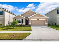 House exterior view showcasing a two-car garage and front yard at 15502 Black Pepper Ln, Odessa, FL 33556