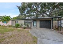Single-story home with a black garage door and landscaped front yard at 664 Frederica Ln, Dunedin, FL 34698