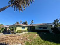 Ranch-style home with green exterior, attached garage, and palm trees at 501 Crystal Dr, Madeira Beach, FL 33708