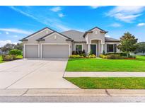 Two-story house with three-car garage, manicured lawn, and mature trees at 913 Buckhurst Dr, Spring Hill, FL 34609