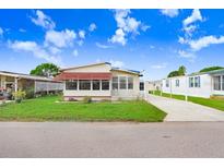 Single-wide manufactured home with a carport and well-manicured lawn at 5251 Astrid Dr, Zephyrhills, FL 33541