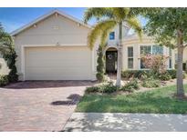 Tan house with brick driveway, palm trees, and manicured landscaping at 1804 Pacific Dunes Dr, Sun City Center, FL 33573