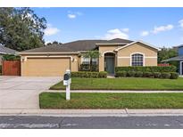 Tan one-story house with a two-car garage and well-manicured lawn at 2913 Red Coat Cir, Brandon, FL 33511