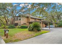 Exterior view of home with multi-car carport, lush landscaping and mature trees at 104 Cypress Pond Rd, Palm Harbor, FL 34683