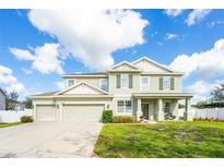 Two-story house with a light-green exterior, two-car garage, and manicured lawn at 1504 Ringmore Ct, Dover, FL 33527