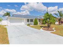 Charming single-story home featuring a well-manicured lawn, driveway, and attached garage under a sunny sky at 907 La Jolla Ave, Sun City Center, FL 33573