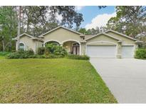 Tan two story home with a three car garage at 13757 Powder Keg Ct, Hudson, FL 34667