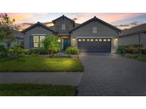 Charming single-Gathering home with a well-manicured lawn and a paved driveway leading to an attached two-car garage at 26810 Weiskopf Dr, Englewood, FL 34223