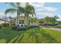 Tan house with palm trees, lush lawn, and a brick paved driveway at 6419 43Rd E Ct, Sarasota, FL 34243