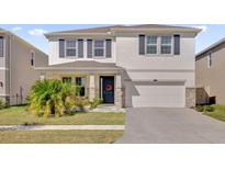 Charming two-story home featuring stone accents, a welcoming front door, and a well-manicured lawn at 30684 Penny Surf Loop, Wesley Chapel, FL 33545