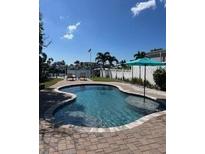 Inviting backyard pool featuring a cool blue umbrella and brick patio, perfect for relaxation at 514 161St Ave, Redington Beach, FL 33708