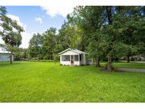 White cottage house with a spacious green lawn at 209 Palm Ln, Brooksville, FL 34601