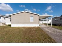 Tan mobile home with carport and paved driveway at 38029 Leondias Dr, Zephyrhills, FL 33542