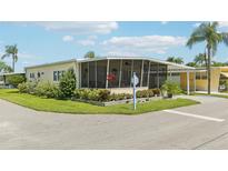 Mobile home with covered porch, landscaped yard, and screened patio at 18675 Us Highway 19 N # 488, Clearwater, FL 33764