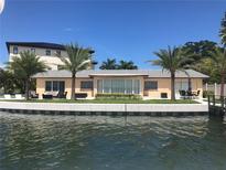 Waterfront home featuring an outdoor seating area, dock access, and lush palm trees in a desirable waterfront location at 239 Punta Vista Dr, St Pete Beach, FL 33706