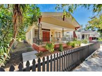 Yellow bungalow with a wrap around porch and black fence at 2905 N 13Th St, Tampa, FL 33605