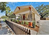 Charming bungalow with a covered front porch, decorative iron railings, and a well-manicured lawn and a picket fence at 2905 N 13Th St, Tampa, FL 33605